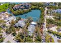 Aerial view showcases a waterfront property with a private pond and mature trees at 3721 Flamingo Ave, Sarasota, FL 34242