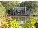 Stunning waterfront home featuring walls of glass, lush greenery, and inviting outdoor seating at 3721 Flamingo Ave, Sarasota, FL 34242