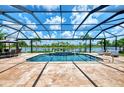 Screened-in pool area with beautiful water view, featuring fountains, tile flooring, and ample lounge space at 20686 Valprato Ct, Venice, FL 34293