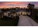 Beautiful two-story home featuring a manicured lawn, brick driveway, and lush landscaping under a vibrant sunset sky at 3407 155Th E Ave, Parrish, FL 34219