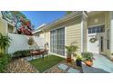 Charming light yellow home with a front patio featuring a cozy seating area, potted plants, and tasteful decor at 7628 Whitebridge Gln, University Park, FL 34201