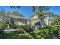 Beautifully landscaped light yellow home with manicured green lawn and mature trees under a clear blue sky at 7628 Whitebridge Gln, University Park, FL 34201