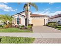 Charming single-story home with a two-car garage, tile roof, and lush tropical landscaping at 23703 Waverly Cir, Venice, FL 34293
