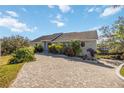 Paver driveway leads to an updated home, framed by lush landscaping, a well-manicured lawn and mature trees at 2458 Whippoorwill Cir, Sarasota, FL 34231