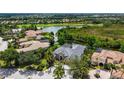Aerial view of a home with a gray roof, lush landscaping, and a pond in the backyard at 13616 Legends Walk Ter, Lakewood Ranch, FL 34202