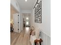 Inviting hallway with light wood floors, decorative bench, and framed Gathering photos on the wall at 2930 61St E Dr, Ellenton, FL 34222