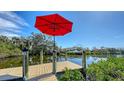Waterfront dock with red umbrella offering picturesque views of the waterway, perfect for boating and relaxation at 603 Barnes Pkwy, Nokomis, FL 34275