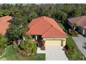 Charming yellow house featuring a well-manicured lawn, lush landscaping, and a red tile roof at 735 Foggy Morn Ln, Bradenton, FL 34212