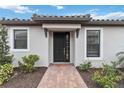Charming single-Gathering home featuring a black front door, decorative tiled roof, and a landscaped walkway at 3016 Formia Ct, Bradenton, FL 34211