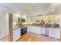 Well-lit kitchen featuring stainless steel appliances, white cabinets, and wood flooring at 3500 El Conquistador Pkwy # 119, Bradenton, FL 34210