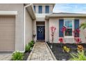 Charming front entrance with a blue door, brick pathway, and colorful plants set against a neutral-toned home exterior at 6428 Devesta Loop, Palmetto, FL 34221