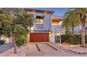 Modern two-story home featuring a wooden garage door, sleek design, well-kept yard and a private entrance gate at 2434 Wood St, Sarasota, FL 34237