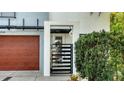 Close-up of the modern home's front gate with a sleek design and lush landscaping and a wood-toned garage at 2434 Wood St, Sarasota, FL 34237