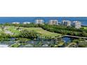 An aerial view of beachfront condos with manicured green spaces and a tennis court at 3060 Grand Bay Blvd # 154, Longboat Key, FL 34228
