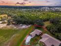 Aerial view of single-story home surrounded by a beautiful green landscape and trees at dusk at 1817 Curry Ave # 57, Nokomis, FL 34275