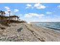 Serene beach view with sandy shore and calm ocean waters under a clear blue sky with scattered clouds at 11 Sunset Dr # 406, Sarasota, FL 34236