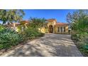 Elegant Mediterranean-style home featuring a brick driveway, arched entry, barrel tile roof and lush landscaping at 1712 Grande Park Dr, Englewood, FL 34223