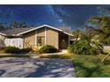 Charming single-story home with a well-manicured lawn and mature trees under a starlit sky at 3443 Tallywood Cir # 7061, Sarasota, FL 34237