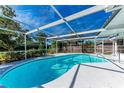 Bright, screened-in pool with sunny patio, lush landscaping, and outdoor seating at 4410 70Th E Dr, Sarasota, FL 34243