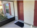 This entryway features a red door and a window with red shutters, all situated on a cozy front porch at 4432 Collingswood Blvd, Port Charlotte, FL 33948