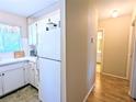 Efficient kitchen with white cabinets, appliances, and a view of the hallway and an adjacent bathroom at 5918 Palm Ln # C33, Bradenton, FL 34207