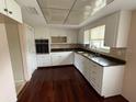 Bright kitchen features wood floors, white cabinets and stainless steel oven at 600 S Neponsit Dr, Venice, FL 34293
