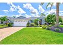 Well-manicured front yard of a beautiful single-story home with a 2-car garage and paver driveway at 7453 Featherstone Blvd, Sarasota, FL 34238