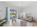 Bright living room with plush seating, a ceiling fan, and sliding glass doors leading to an outdoor pool at 7453 Featherstone Blvd, Sarasota, FL 34238