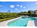 Backyard features a pristine swimming pool with a spa, surrounded by lush landscaping, offering a private oasis at 7453 Featherstone Blvd, Sarasota, FL 34238