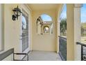 A serene, covered balcony with stucco arches, metal railings, and a tranquil view of palm trees and residential architecture at 1605 Napoli W Dr, Sarasota, FL 34232