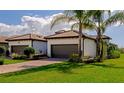 This exterior view captures the home's clean curb appeal, tile roof, brown garage doors, and lush green lawn at 12251 Myrtle Bay Ct, Sarasota, FL 34238