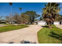 Inviting single-story home with an attached garage, spacious driveway, lush lawn, and mature trees at 5500 Bayou Grande Ne Blvd, St Petersburg, FL 33703