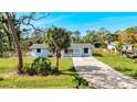 Charming single-story home with a well-maintained yard, light blue siding and a gravel driveway at 712 N Elm St, Englewood, FL 34223