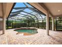 Indoor screened-in pool with brick pavers and lush greenery, perfect for year-round enjoyment at 2111 152Nd E Ct, Bradenton, FL 34212