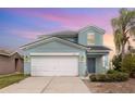 Two-story home featuring a two-car garage, lovely landscaping, and a welcoming front porch with a calming sky backdrop at 2347 Richwood Pike Dr, Ruskin, FL 33570