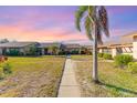 Charming community featuring a well-manicured lawn and tropical palm trees against a sunset sky at 6314 29Th W Ave, Bradenton, FL 34209