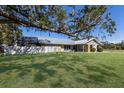 A home with a metal roof and stone accents is surrounded by a green lawn and shaded by a grand oak tree at 6615 13Th E Ave, Bradenton, FL 34208