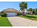 A well-maintained house featuring a pristine lawn, long driveway, and lush green landscaping at 1364 Berkshire Ct, Venice, FL 34292