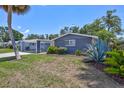 Inviting front yard showcasing lush greenery, a charming blue home exterior, and a convenient attached carport at 2321 Terry Ln, Sarasota, FL 34231