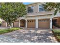 Townhome garages with neutral paint, white trim and brick driveways are shaded by mature trees at 4007 Overture Cir, Bradenton, FL 34209
