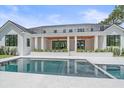 Luxurious backyard with a sparkling pool, covered patio, and meticulously maintained landscaping at 656 Tropical Cir, Sarasota, FL 34242