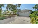 Beautiful home featuring a wide driveway leading to a two-car garage, complemented by lush landscaping at 92 Tall Trees Ct, Sarasota, FL 34232