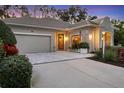 Beautiful single-story home with lush landscaping, a paver driveway, and warm exterior lighting at dusk at 1359 Tearose Pl, Sarasota, FL 34239
