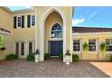 Stunning home featuring a unique arched entryway, blue double doors, and a well-manicured landscape at 273 Portofino Dr, North Venice, FL 34275