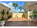 Private patio features a tiered fountain, manicured shrubbery, and brick paver flooring at 273 Portofino Dr, North Venice, FL 34275