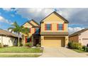 Charming two-story home featuring a two-car garage, manicured lawn, tropical palm tree, and red shutters adding a pop of color at 14318 Fissore Blvd, Wimauma, FL 33598
