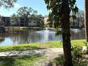 Scenic view of a tranquil pond with a fountain, surrounded by lush greenery and mature trees in a serene community setting at 315 30Th W Ave # 101B, Bradenton, FL 34205