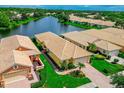 Aerial view of a lovely house with a tile roof and lush landscaping on a lakefront property at 4244 Reflections Pkwy, Sarasota, FL 34233