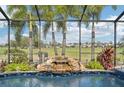 Pool area with screened enclosure, rock waterfall feature, lush landscaping, and golf course views at 7812 Birdie Bend Way, Sarasota, FL 34241