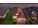 Aerial view of a home with a tile roof and well-manicured lawn near the water at 3023 Vittorio Ct, Lakewood Ranch, FL 34211